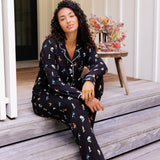 Model wearing Long-Sleeved Women's Pajama Set in Midnight Wildflower print sitting on outdoor steps ---PJ 4