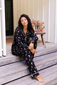 Model wearing Long-Sleeved Women's Pajama Set in Midnight Wildflower print sitting on outdoor steps ---PJ 4