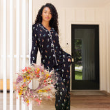 Model wearing Long-Sleeved Women's Pajama Set in Midnight Wildflower print standing outdoors holding a flower wreath ::: Model is 5'10" wearing size S /// ---PJ 2