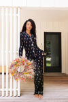 Model wearing Long-Sleeved Women's Pajama Set in Midnight Wildflower print standing outdoors holding a flower wreath ::: Model is 5'10" wearing size S /// ---PJ 2
