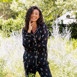 Model smiling outdoors between bushes in Long-Sleeved Women's Pajama Set in Midnight Wildflower print