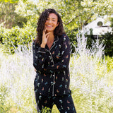 Model smiling outdoors between bushes in Long-Sleeved Women's Pajama Set in Midnight Wildflower print