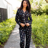 Model wearing Long-Sleeved Women's Pajama Set in Midnight Wildflower print standing outdoors surrounded by trees ---1605 1