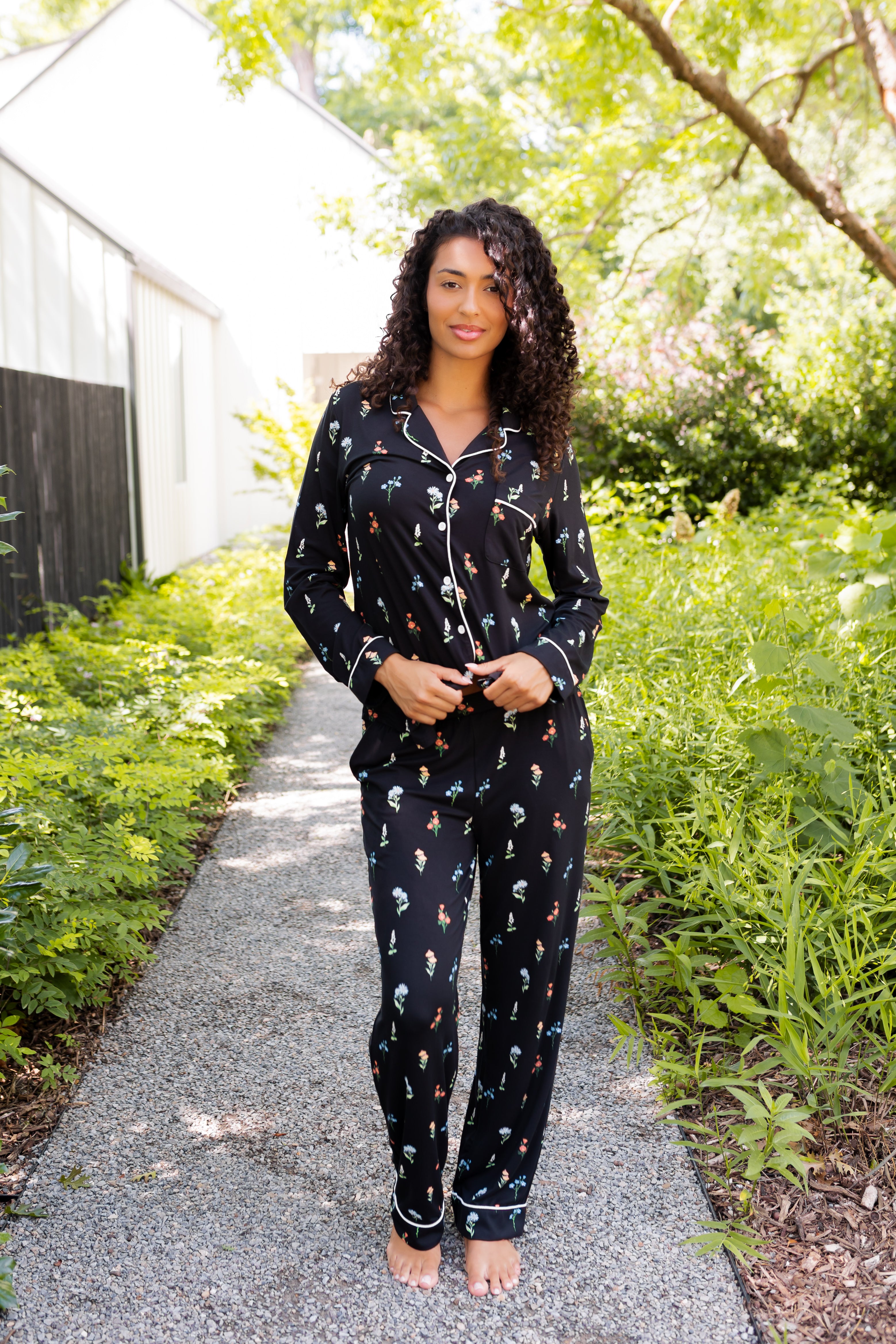 Model wearing Long-Sleeved Women's Pajama Set in Midnight Wildflower print standing outdoors surrounded by trees ---1605 1