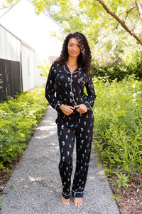 Model wearing Long-Sleeved Women's Pajama Set in Midnight Wildflower print standing outdoors surrounded by trees ---1605 1