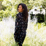 Model posing outdoors in bushes back side of Long-Sleeved Women's Pajama Set in Midnight Wildflower print
