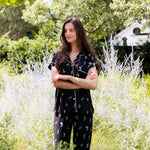 Model standing outdoors in bushes wearing Women's Short Sleeve Cropped Pajama Set in Midnight Wildflower print