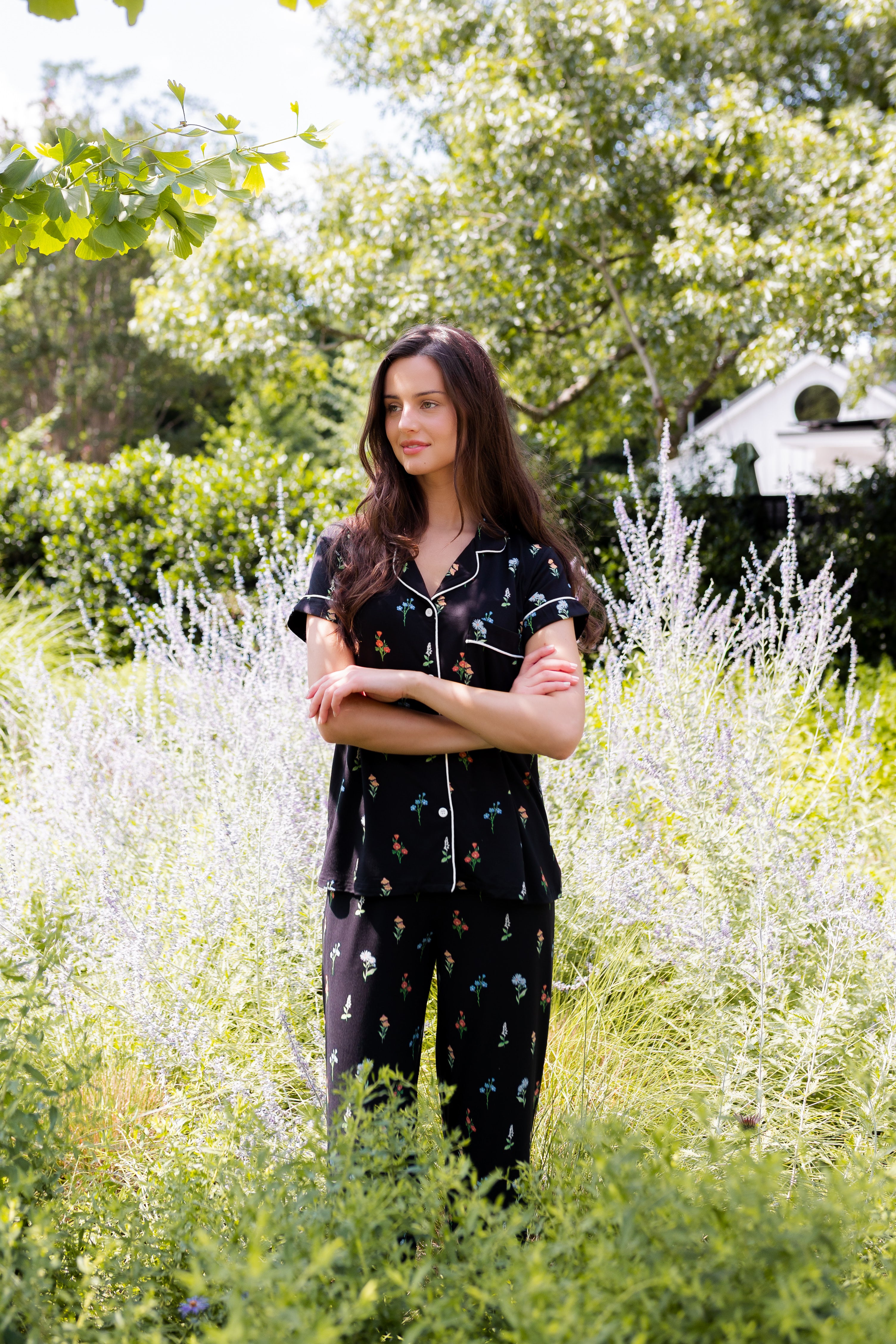 Model standing outdoors in bushes wearing Women's Short Sleeve Cropped Pajama Set in Midnight Wildflower print