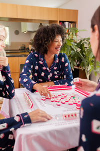 Three women playing a mahjong game together in a kitchen.