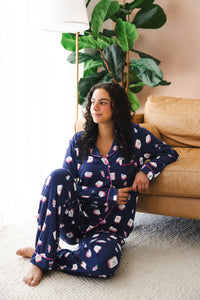 Model sitting in front of sofa and large plant wearing Women's long sleeve pajama set in Navy Mahjong 