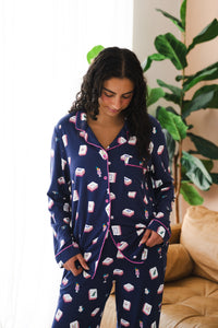 Woman looking downwards in front of a large plant while modeling the  Women's long sleeve pajama set in Navy Mahjong 