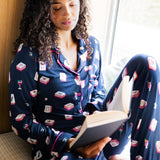 Woman in pajamas reading a book by a window