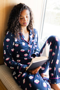 Woman in pajamas reading a book by a window