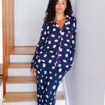 Woman wearing navy pajamas with pink mahjong pattern standing on a staircase.