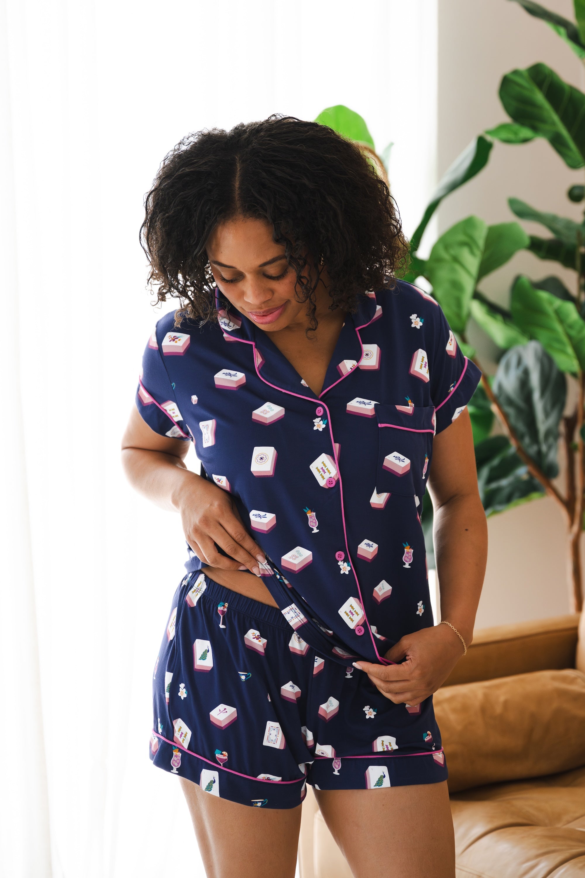 Woman looking downwards while modeling the Women's short sleeve pajama set in Navy Mahjong with a plant in the back ground

