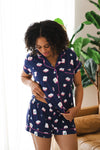 Woman looking downwards while modeling the Women's short sleeve pajama set in Navy Mahjong with a plant in the back ground

::: Model is 5'6" wearing size M ///
