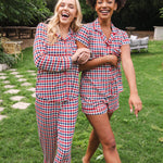 Smiling and hugging models walking in a yard wearing the Women's Long Sleeve Pajama Set and Short Sleeve Pajama Set in Patriotic Gingham 