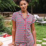 Model standing outside next to a picnic table while wearing the Women's Short Sleeve Pajama Set in Patriotic Gingham  ::: Model is 5'9"" wearing size S ///
