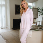 Woman in light pink pajama set standing in a modern living room.