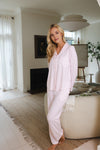 Woman in light pink pajama set standing in a modern living room.