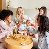 A group of models wearing Long sleeved Women's Pajama Set and women's short sleeve pajama set in Blush Sushi and Ice Sushi print while enjoying a meal of sushi on a table