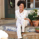 Woman in pajamas sitting on a porch with potted plants
