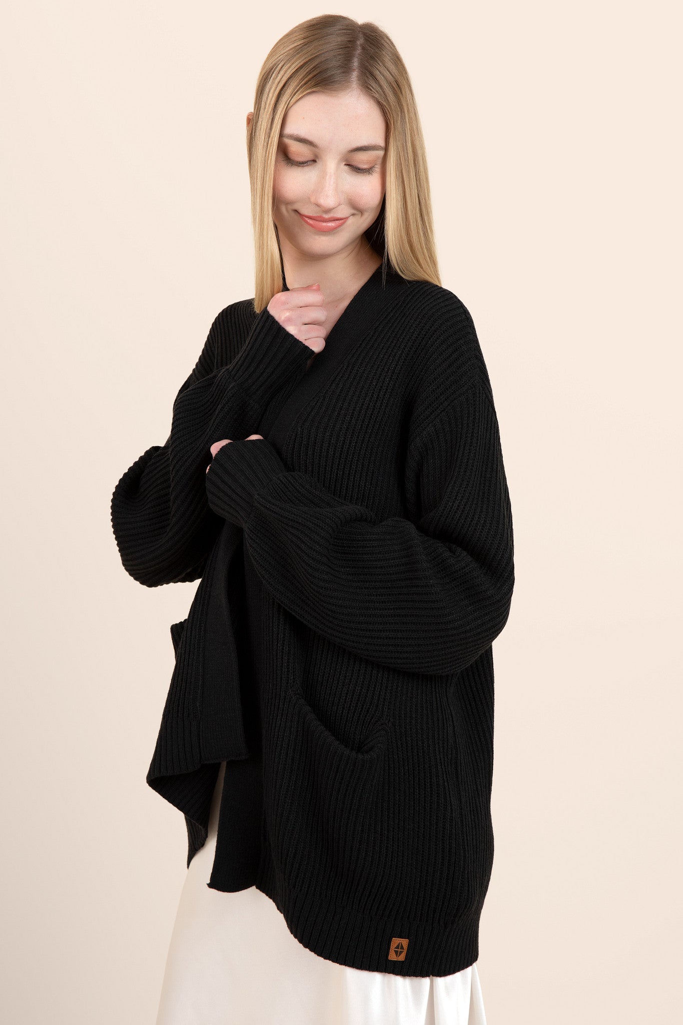 Model wearing black chunky knit oversized cardigan over a silk dress
