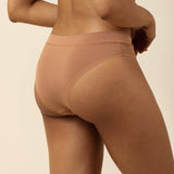 Person wearing a brown bra and cheeky underwear on a beige background