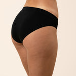 Black underwear worn by a person on a beige background