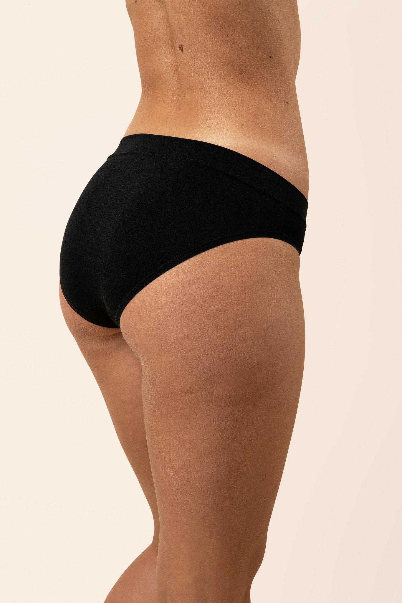 Black underwear worn by a person on a beige background