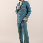 Man modeling button up long sleeve pajamas in a teal blue color with white trim