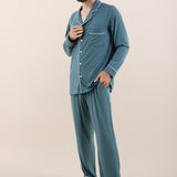Man modeling button up long sleeve pajamas in a teal blue color with white trim