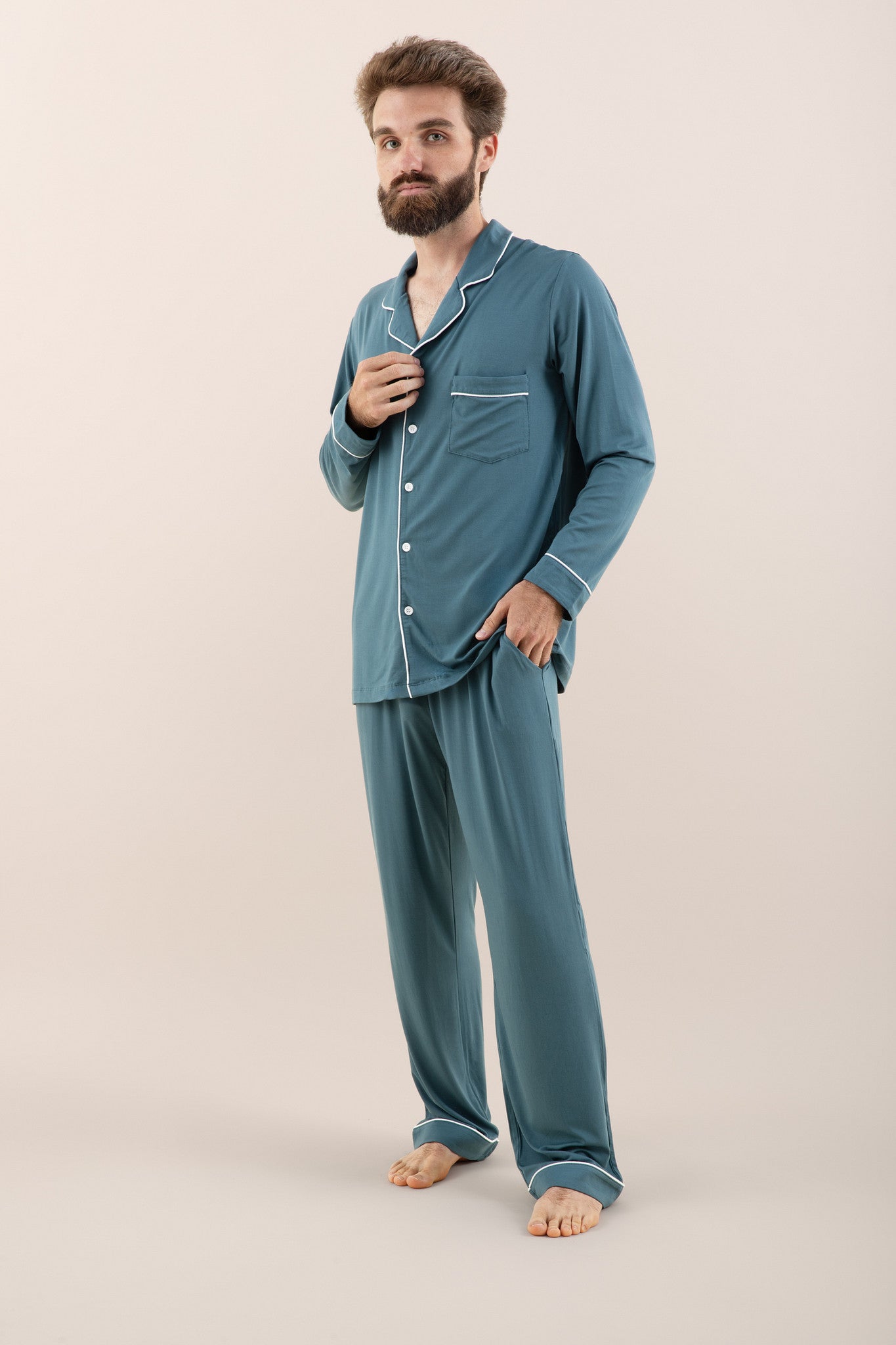 Man modeling button up long sleeve pajamas in a teal blue color with white trim