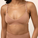 Woman wearing a tan bamboo nursing bra against a beige background