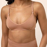 Woman wearing a tan bamboo nursing bra against a beige background