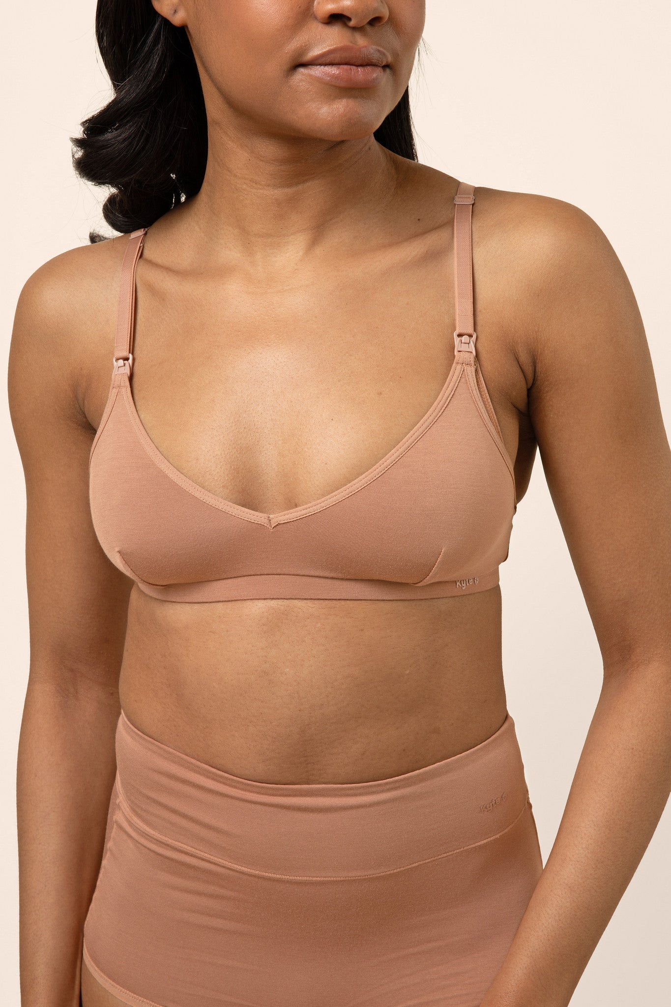 Woman wearing a tan bamboo nursing bra against a beige background