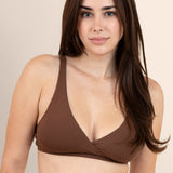 Woman wearing a brown cross front bralette against a beige background
