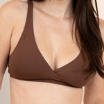 Woman wearing a brown bralette against a beige background