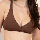 Woman wearing a brown bralette against a beige background
