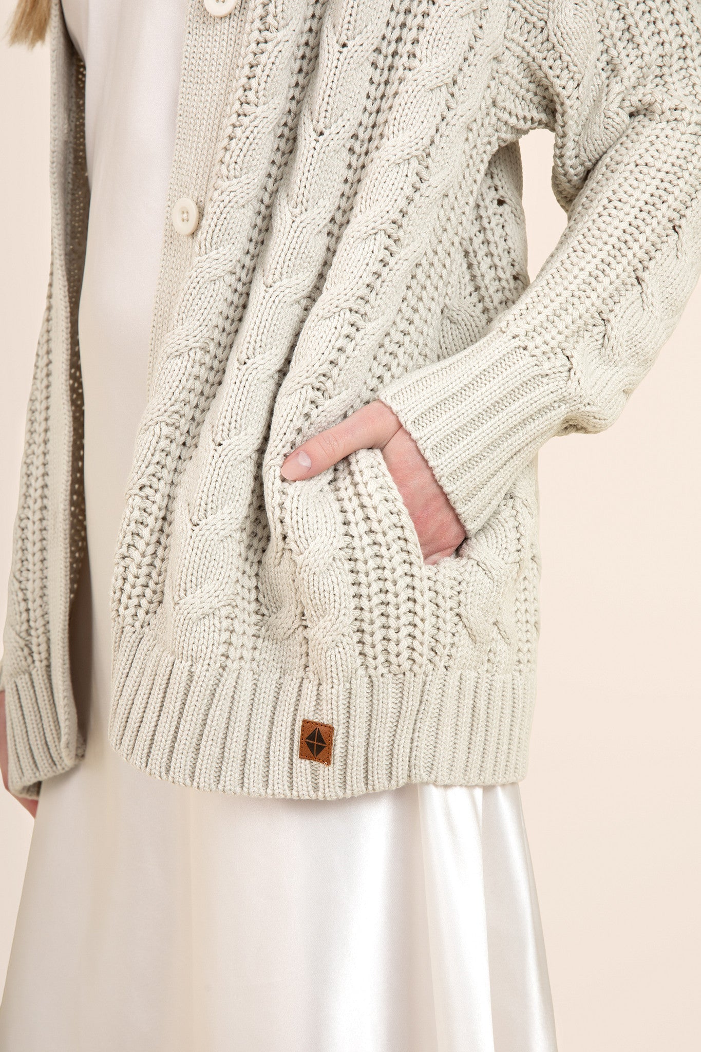 Close up of oat colored cable knit cardigan