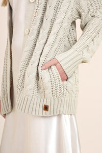 Close up of oat colored cable knit cardigan