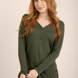 Woman wearing a green long-sleeve top and pants on a beige background