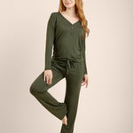 Woman wearing a green long-sleeve top and pants on a beige background