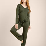 Woman wearing a green long-sleeve top and pants on a beige background