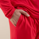 Person wearing a red outfit with one hand in the pocket against a beige background