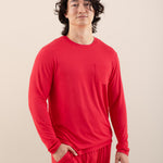 Man wearing a red long-sleeve shirt and pants on a beige background