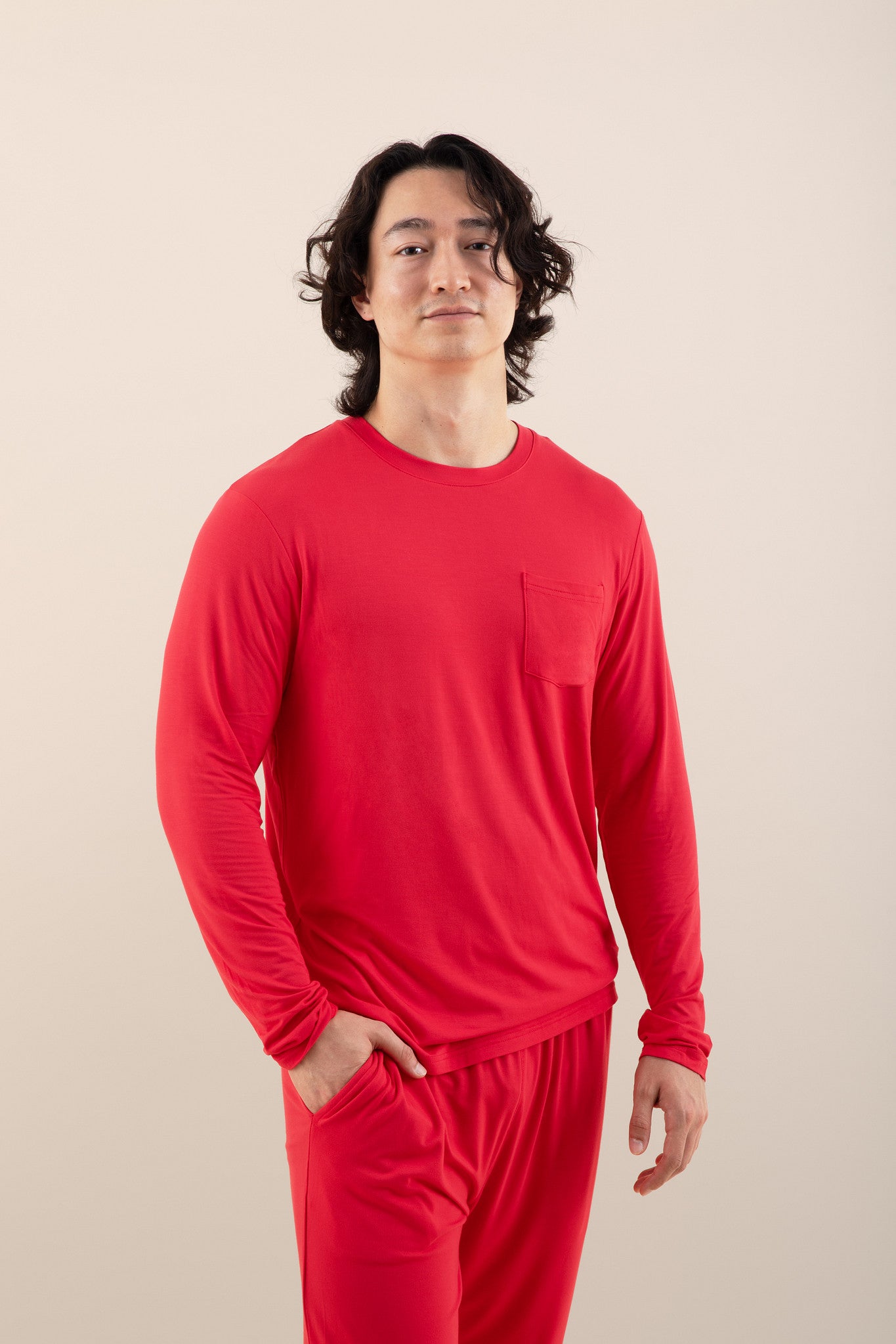 Man wearing a red long-sleeve shirt and pants on a beige background