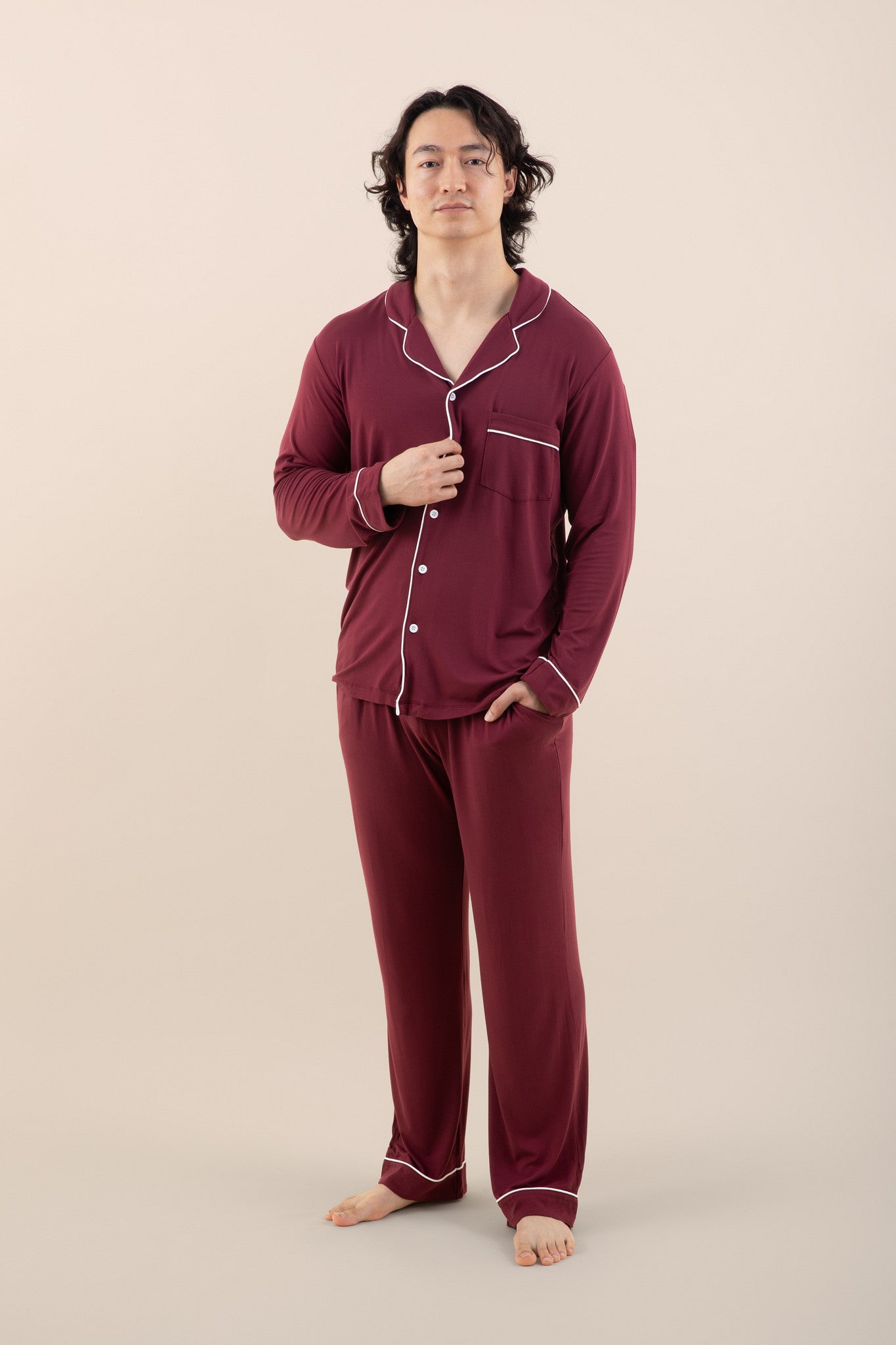 Person wearing burgundy pajamas with white piping on a beige background