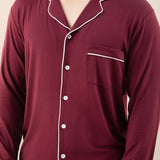 Maroon pajama set with white piping on a neutral background