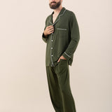 Man wearing green pajamas with white piping on a beige background